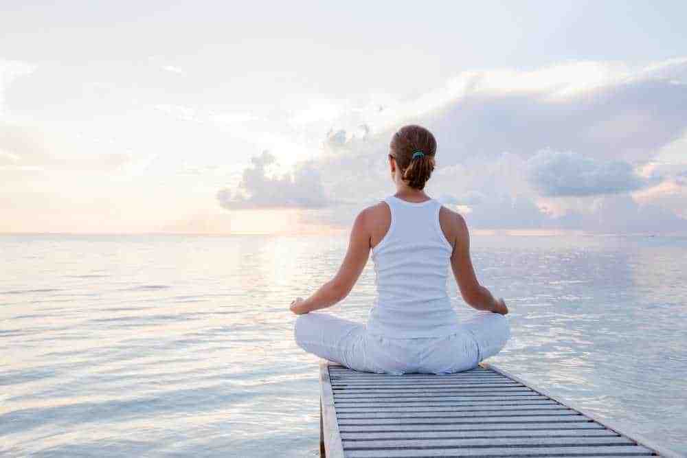 Werte und Handeln - Frau meditiert am See